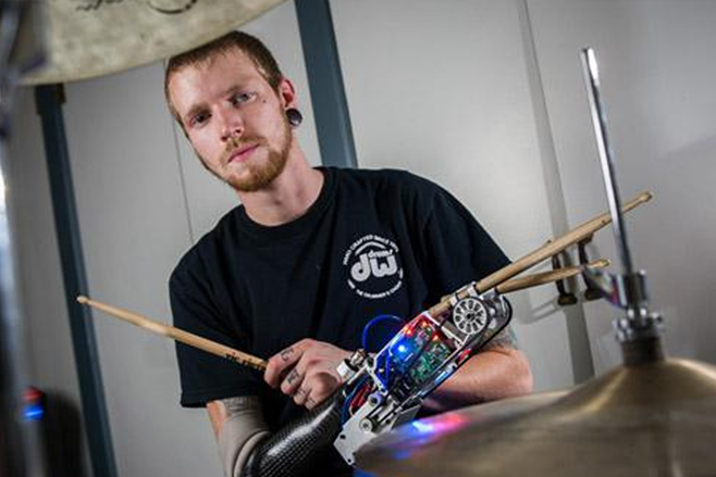 person with a robotic arm playing drums